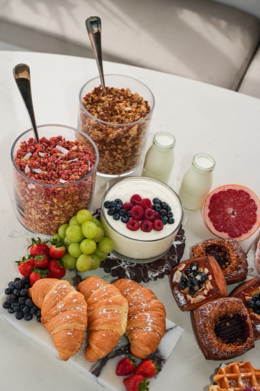 Brunch grazing table with granola, yoghurt, fresh fruit, pastries and juice