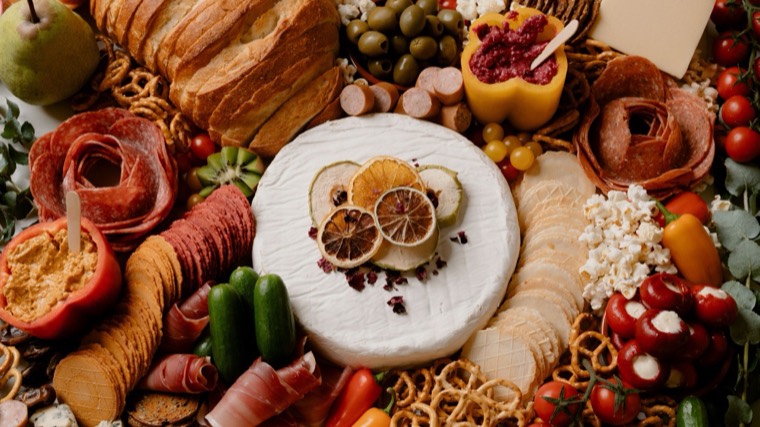 Savoury grazing table with a brie wheel, cured meats, olives, pickles and bread