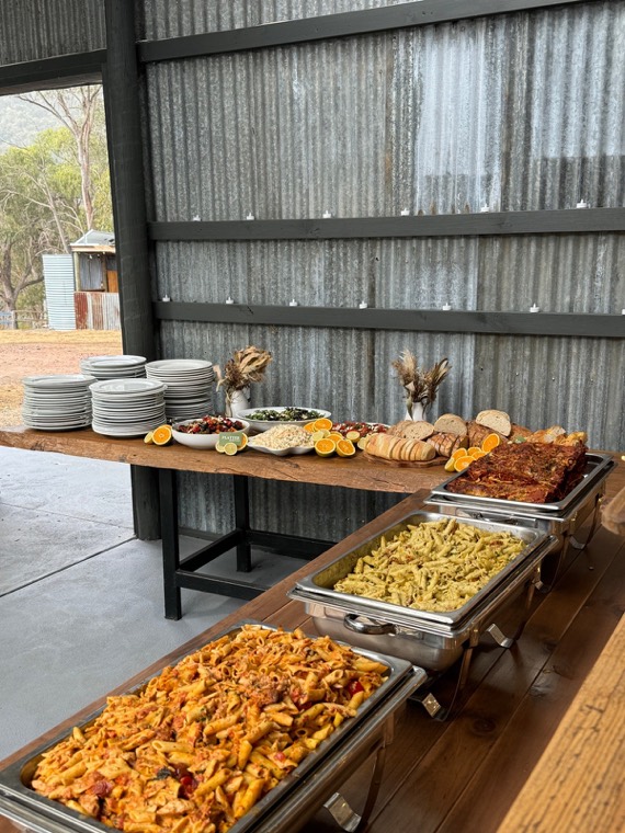 Catering buffet with trays of pasta and a grazing table at an event