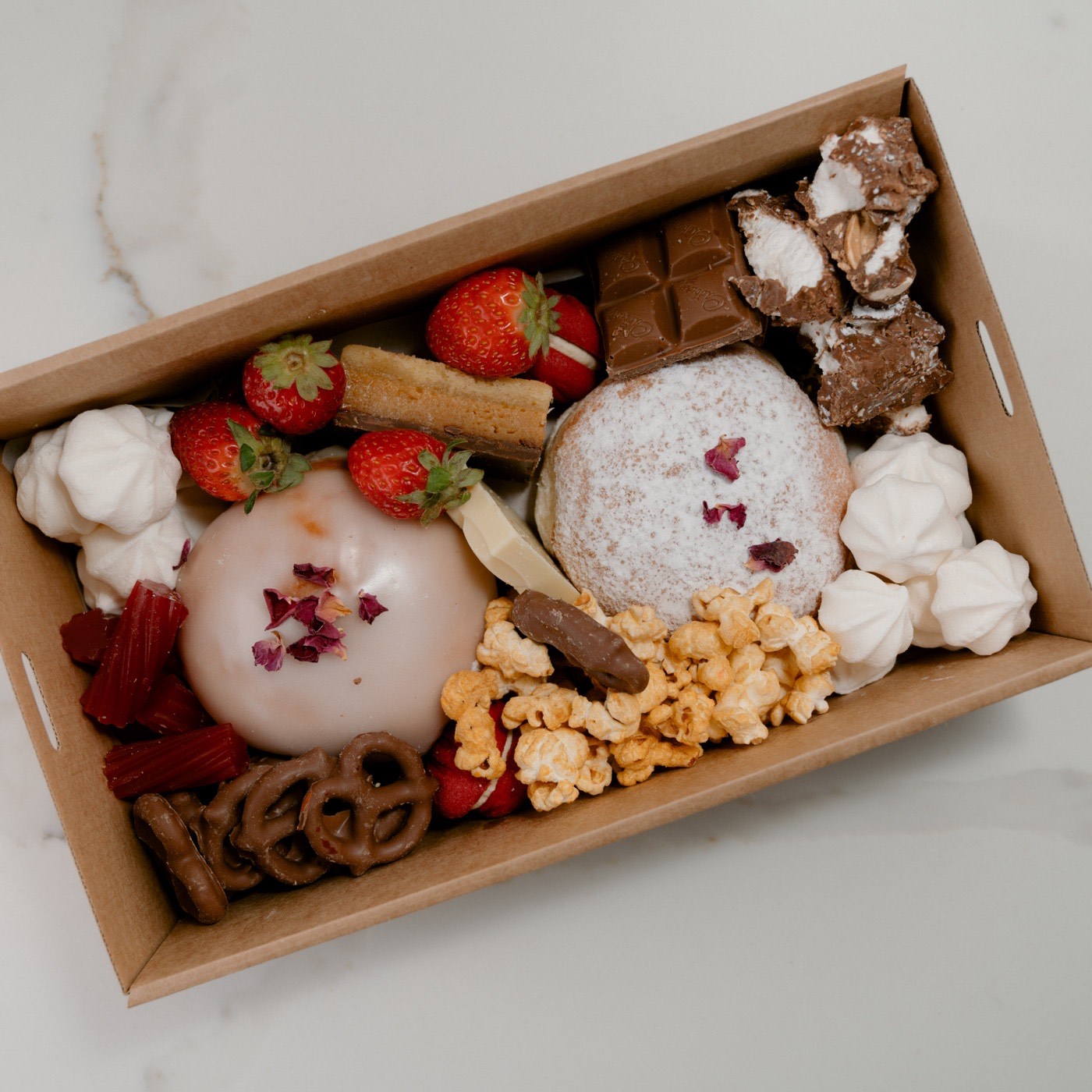 Sweet grazing box with a donut, chocolate, meringues, popcorn and strawberries